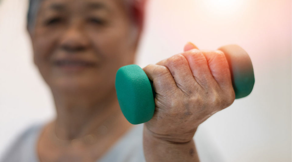 Senior elderly woman hand holding dumbbell in physical therapy session